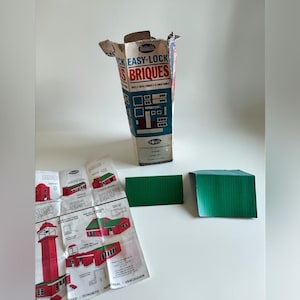 May include: A vintage Reliable Easy-Lock Bricks construction set box with blue and white graphics, a folded instruction manual featuring red building illustrations, and two rectangular green plastic roof pieces for assembly.