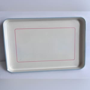 Peut inclure: Un plateau de service rectangulaire avec une base couleur crème et un bord bleu clair. Le centre du plateau présente un fin contour rectangulaire rose. Le plateau a des coins arrondis et une finition lisse et brillante sur toute sa surface.