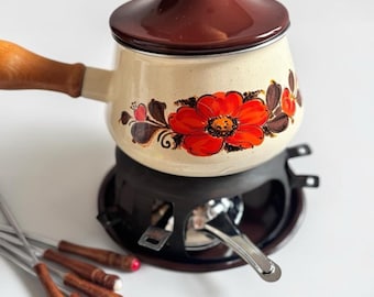 Juego de fondue vintage con olla de esmalte floral, soporte y tenedores estilo retro.
