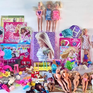Op de afbeelding: Een verzameling Barbie-poppen en accessoires, waaronder poppen in verschillende outfits, boeken en speelgoed. De afbeelding toont een verscheidenheid aan kleuren, waaronder roze, blauw en wit, met verschillende Barbie-poppen die rechtop staan.