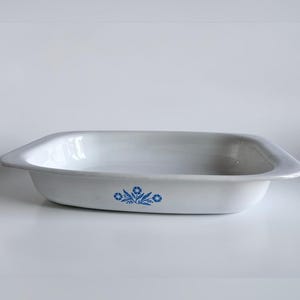 May include: White rectangular ceramic baking dish with a blue floral pattern. The dish has a gently curved rim. The blue floral design is located on the front of the dish.