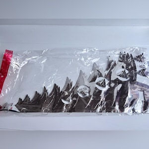 Peut inclure: Un paquet contenant des découpes décoratives en métal représentant une chaîne de montagnes. Les découpes sont marron foncé avec des accents argentés et des détails circulaires. L'emballage est scellé avec une fermeture rayée rouge et blanche.