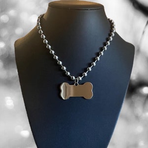 May include: A silver chain necklace with a silver bone-shaped pendant. The pendant is blank and can be engraved.