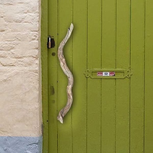 May include: A vibrant green wooden door with a driftwood handle, set in a cream-coloured brick wall. The door features a mail slot and is part of a building with a blue painted base. The door has a window above.