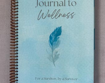 May include: A blue journal with a watercolor background and a feather design. The journal is titled "Journal to Wellness" and has the text "For a Survivor, by a Survivor" at the bottom.