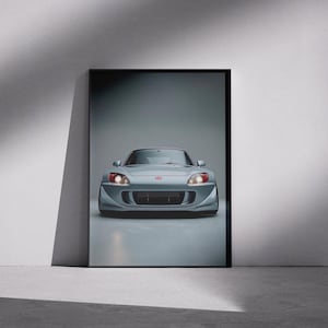 May include: A framed print featuring a silver sports car with red headlights. The car is centered in the frame, showcasing its sleek design. The image is set against a gray backdrop, highlighting the car's form.