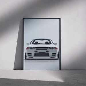 May include: A framed vertical wall art print featuring a front-facing view of a white Nissan Skyline GT-R R32 sports car. The vehicle is depicted with its signature rectangular headlights, a prominent front grille, and a low-profile bumper design.