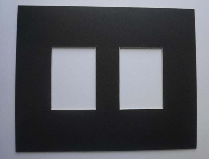 May include: A black picture mat with two rectangular openings. The mat has a textured surface and white backing visible through the openings. Ideal for displaying two photos or artwork.