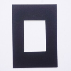 May include: Black mat board with a white rectangular opening in the center. The mat board is designed to be used for framing photographs or artwork.