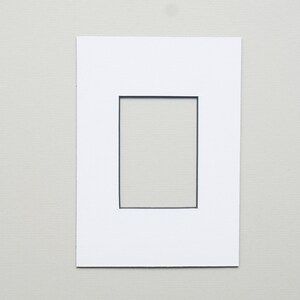 May include: White mat with a black rectangular opening in the center.