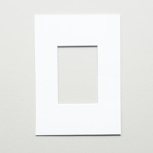 May include: A white mat with a rectangular opening in the center. The mat is designed to hold a photo or artwork.