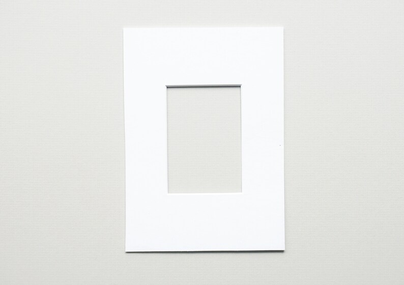 May include: A white mat with a rectangular opening in the center. The mat is designed to hold a photo or artwork.