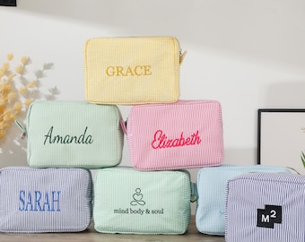 May include: Six different patterned zippered pouches with various embroidered names and phrases. The pouches are yellow, green, pink, blue, and white.