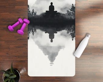 May include: A white yoga mat with a black and white image of a person meditating in front of a lake and mountains. The image is reflected in the water.