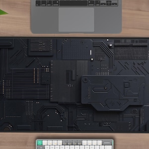 May include: Black and grey mouse mat with a circuit board design. The mouse mat is rectangular and has a smooth surface.