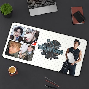 Könnte beinhalten: Weißes rechteckiges Schreibtisch-Pad mit Bildern einer Person, einer schwarzen Rosen-Grafik und dem Namen "TAEHYUNG". Das Pad hat einen schwarzen Rand und ein gepunktetes Muster. Ein Laptop, ein Notizbuch und eine Kaffeetasse sind ebenfalls sichtbar.