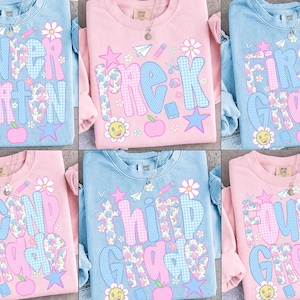 May include: A collection of six crewneck sweatshirts in light blue and light pink, each featuring school-themed graphics including the words Kindergarten, Pre-K, First Grade, Second Grade, Third Grade, and Fourth Grade with floral and plaid patterns.