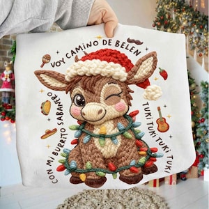 May include: Embroidered Christmas-themed donkey design on a white fabric. The donkey wears a Santa hat and is adorned with colorful Christmas lights. Text includes "Voy Camino De Belen" and "Con Mi Burrito Sabanero."