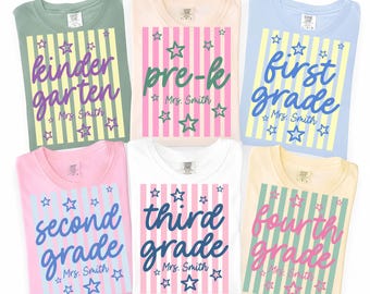 May include: Six t-shirts in sage green, peach, light blue, pink, white, and yellow. Each features a vertical striped rectangle with stars and text reading kindergarten, pre-k, first grade, second grade, third grade, or fourth grade, plus Mrs. Smith.