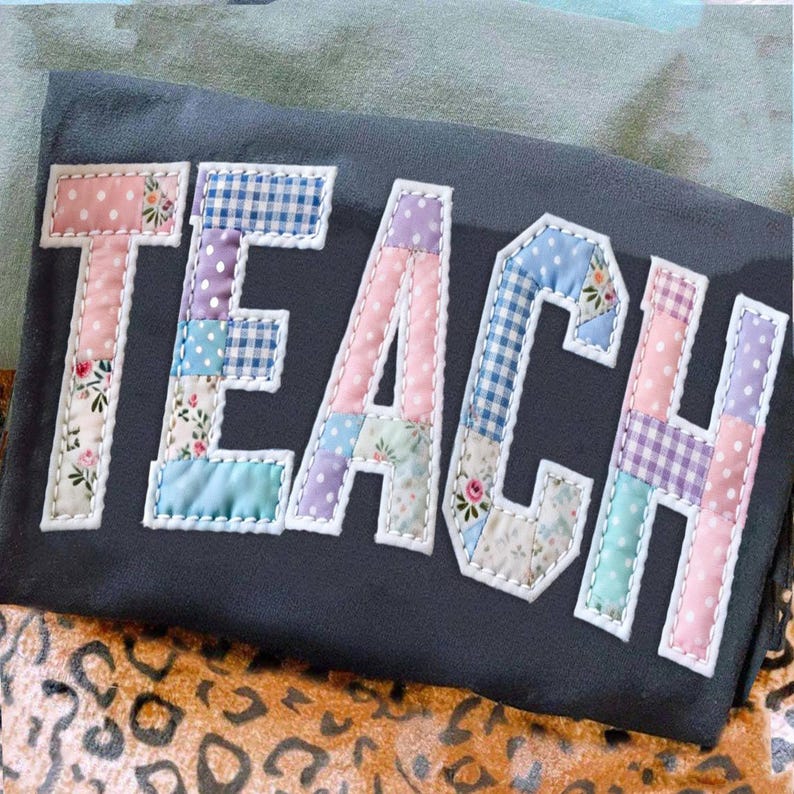 Może przedstawiać: Ciemnoszary element materiału z napisem "TEACH" naszytym kolorowymi literami z patchworku. Każda litera składa się z r&oacute;żnych wzorzystych tkanin, w tym kwiatowych, w kropki i w kratkę, z białymi przeszyciami.