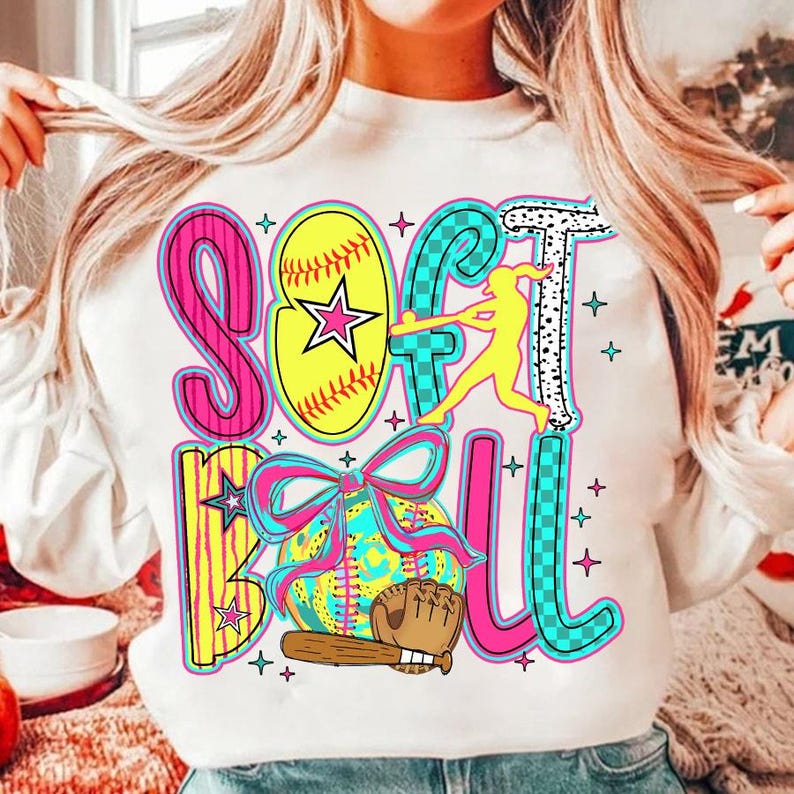 May include: White sweatshirt with a colorful graphic design that says "Softball" with a softball, bat, glove, and a player hitting a ball.