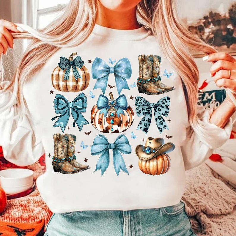 May include: White sweatshirt with a blue, brown, and white pumpkin, cowboy boot, and bow design. The design features a variety of pumpkins, bows, and cowboy boots.