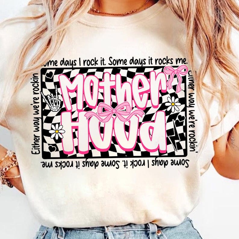 Peut inclure: T-shirt cr&egrave;me avec un motif rose et blanc "Motherhood" sur fond damier noir et blanc. Le motif comprend des n&oelig;uds roses, des fleurs et les phrases "Either way we're rockin'" et "Some days I rock it. Some days it rocks me."