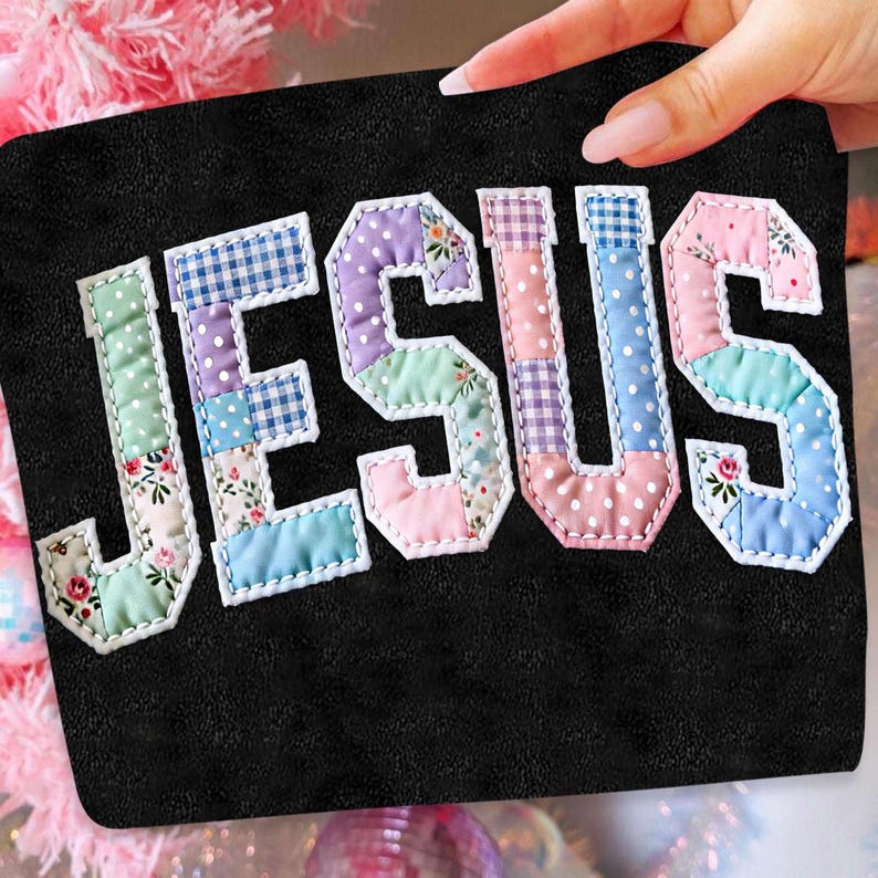 May include: Black pouch with the word "JESUS" appliqued in colorful patchwork fabric. The letters are outlined in white stitching, and the background is a solid black. The patchwork includes floral, polka dot, and gingham patterns.