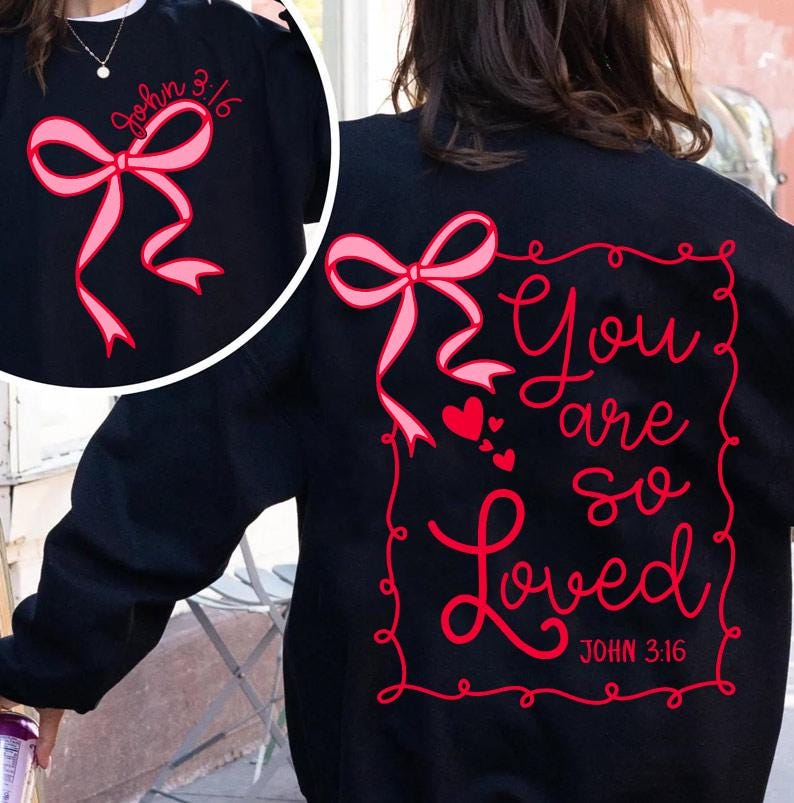 May include: Black sweatshirt with a pink bow and the text "John 3:16" on the front. The back of the sweatshirt has a pink bow and a red frame with the text "You are so Loved" and "John 3:16" inside.