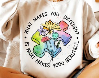 May include: A white sweatshirt with a colorful puzzle piece design and the text "What makes you different is what makes you beautiful."