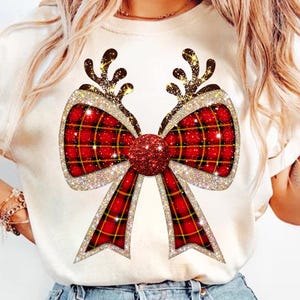 Könnte beinhalten: Weißes T-Shirt mit einer roten und goldenen Glitzer Schleife und Rentiergeweih. Die Schleife ist kariert und hat eine rote Glitzermitte.