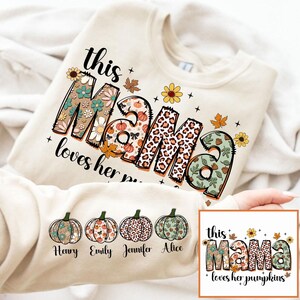Puede incluir: Una sudadera beige con el texto "this mama loves her pumpkins" en un dise&ntilde;o floral y de leopardo. La sudadera tiene cuatro calabazas con los nombres "Henry", "Emily", "Jennifer" y "Alice" impresos debajo.
