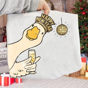 May include: White fabric with a cartoon goose wearing a gold crown that says "Happy New Year." The goose is holding a champagne glass. A gold disco ball hangs from a string. Festive holiday theme.