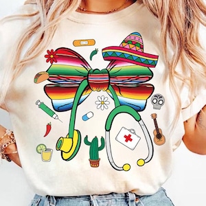 Peut inclure: T-shirt blanc avec un nœud coloré de style mexicain, un stéthoscope et d'autres petits détails comme un cactus, un taco et une trousse de premiers soins.