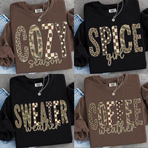 Puede incluir: Cuatro sudaderas de cuello redondo en marrón y negro, cada una con un collar plateado y un estampado gráfico. Los diseños incluyen las palabras COZY season, SPICE girl, SWEATER weather y COFFEE weather, con letras en patrones de leopardo, camuflaje y cuadros.
