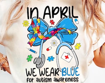 May include: White t-shirt with a blue ribbon, a stethoscope, and puzzle pieces. The text "In April We Wear Blue for autism awareness" is printed on the shirt.