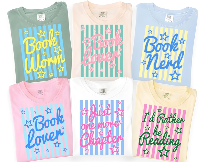 May include: Six t-shirts in various colors, each with a unique book-themed graphic. The shirts feature phrases like "Book Worm," "Book Lover," and "I'd Rather be Reading," with star and stripe designs. The shirts are folded and displayed.