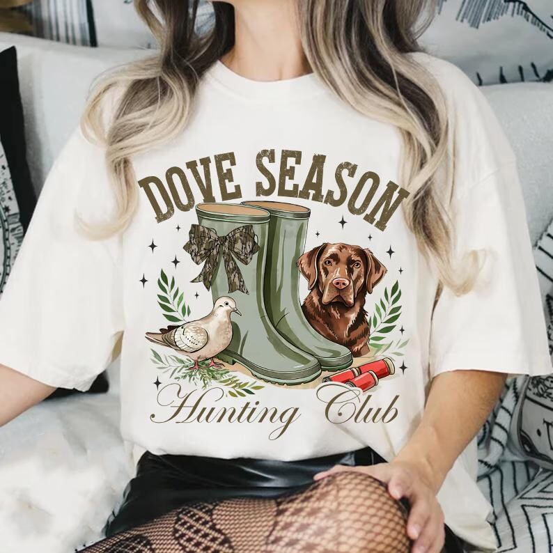 May include: White t-shirt with a brown and white dove, a brown dog, and green rain boots. The text on the shirt says "Dove Season Hunting Club".