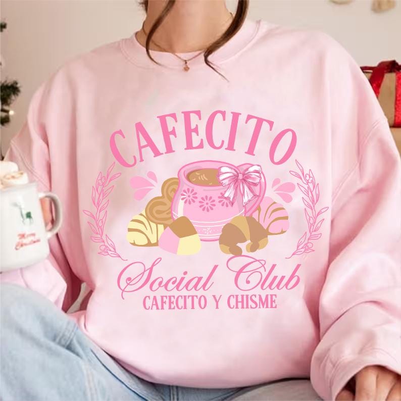 May include: Pink sweatshirt with a graphic design of a coffee cup and pastries with the text "Cafecito Social Club Cafecito y Chisne"