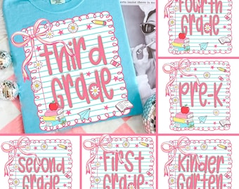May include: A light blue t-shirt with a pink "Third Grade" graphic. The graphic includes a stack of books, an apple, a paper airplane, and a pencil. Additional graphics include daisies and a pink bow.