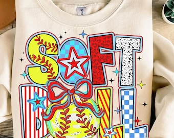 Könnte beinhalten: Cremefarbenes Sweatshirt mit dem Wort "SOFTBALL" in einem farbenfrohen, verspielten Design. Die Buchstaben sind mit Baseball- und Sternmotiven verziert, darunter eine rote Schleife und ein gelber Softball.