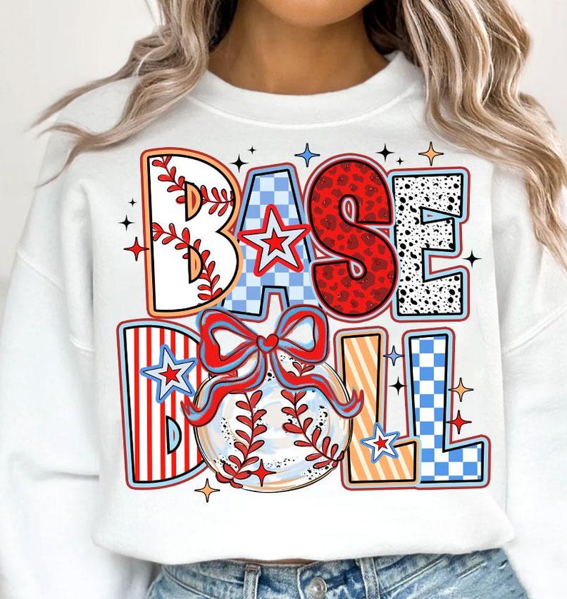 May include: White sweatshirt with a colorful graphic design that says "BASEBALL" with a baseball and a bow. The graphic is made up of different patterns like stripes, polka dots, and checkered.