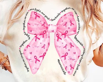 May include: White t-shirt with a pink ribbon bow design. The ribbon is patterned with pink hearts and the words "Hope" and "Love". The text around the bow reads "one fight, one goal! love heals together we rise hope unites us unstoppable victory hope faith wins #teamnicole".
