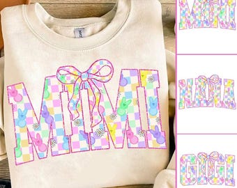 May include: A light beige sweatshirt with a pink and white checkered design featuring the word "MIMI" with a pink bow on top. The letters are decorated with pastel-colored bunny shapes.