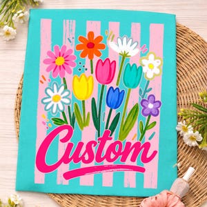 May include: A teal and pink floral design with the word "Custom" in a cursive font. The design features a variety of colorful flowers, including daisies, tulips, and other blooms, set against a striped background.