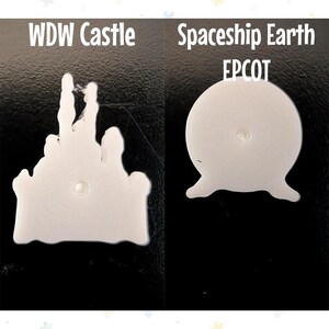 Op de afbeelding: Twee witte plastic ornamenten. E&eacute;n is een kasteel met de tekst "WDW Castle" erboven. De andere is een bol met drie poten, met de tekst "Spaceship Earth EPCOT" erboven. Beide staan op een zwarte achtergrond.