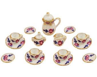 May include: Miniature porcelain tea set with a white base, adorned with red floral patterns and blue accents. The set includes a teapot, sugar bowl, creamer, cups, and saucers, all with gold trim. A charming addition to any dollhouse.