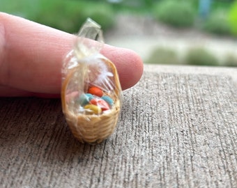 May include: A miniature wicker basket filled with colorful Easter eggs, wrapped in clear plastic.