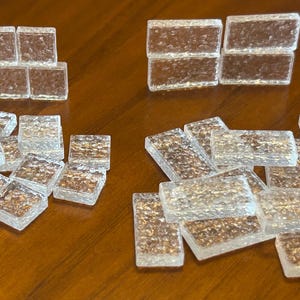 May include: A collection of clear glass tiles with a textured surface. The tiles are arranged in different patterns and sizes.