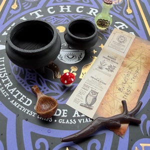 May include: A set of two black plastic cauldrons, a small glass bottle labeled Dragon Scales, a red and white mushroom figurine, a brown wooden-textured spoon, and a paper scroll titled Mysterious Magic Recipe with an owl illustration.
